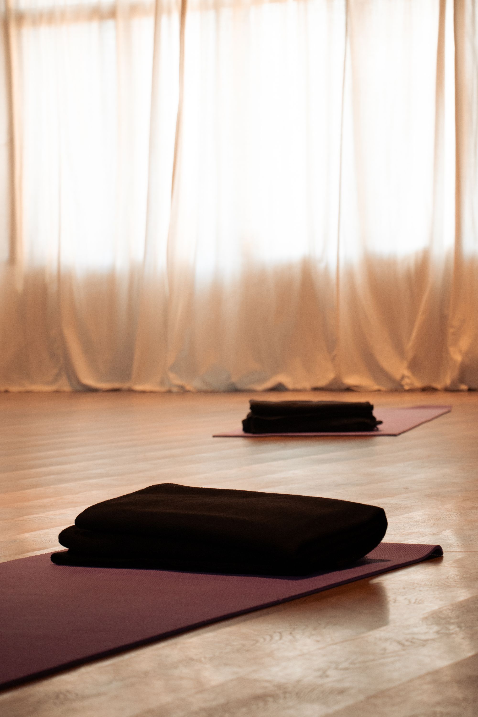 Ruhiges Yogastudio mit warmem Nachmittagslicht, Yogamatten auf Holzboden